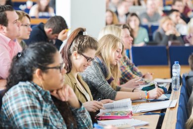 Seitlicher Blick auf eine Gruppe von Studenten unterschiedlichen Alters und Geschlechts. Die Szene findet in einem Hörsaal der Fachhochschule Münster statt.