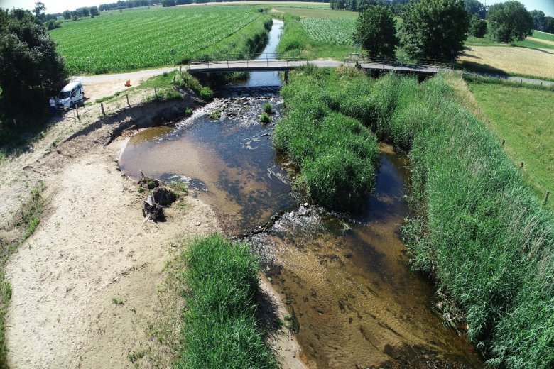 Luftbild mit neu gestalteten Uferzonen und einer Brücke im Hintergrund
