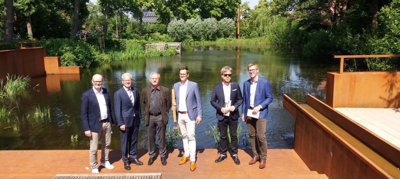 Sechs Menschen stehen vor dem Dorfteich Asbeck