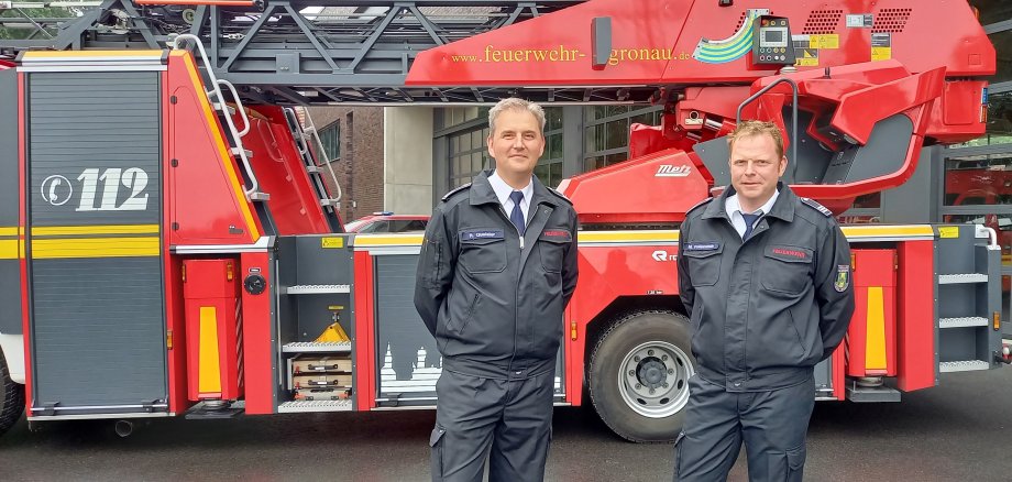 Zwei Feuerwehrleute vor einem Feuerwehrfahrzeug