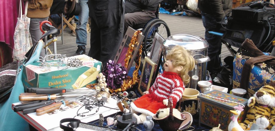 Das Foto zeigt einen Stand auf einen Flohmarkt mit ganz vielen Artikeln zum Verkauf.