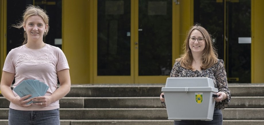 Zwei Frauen vor dem Rathaus mit dem Aufruf Wahlhelfer gesucht