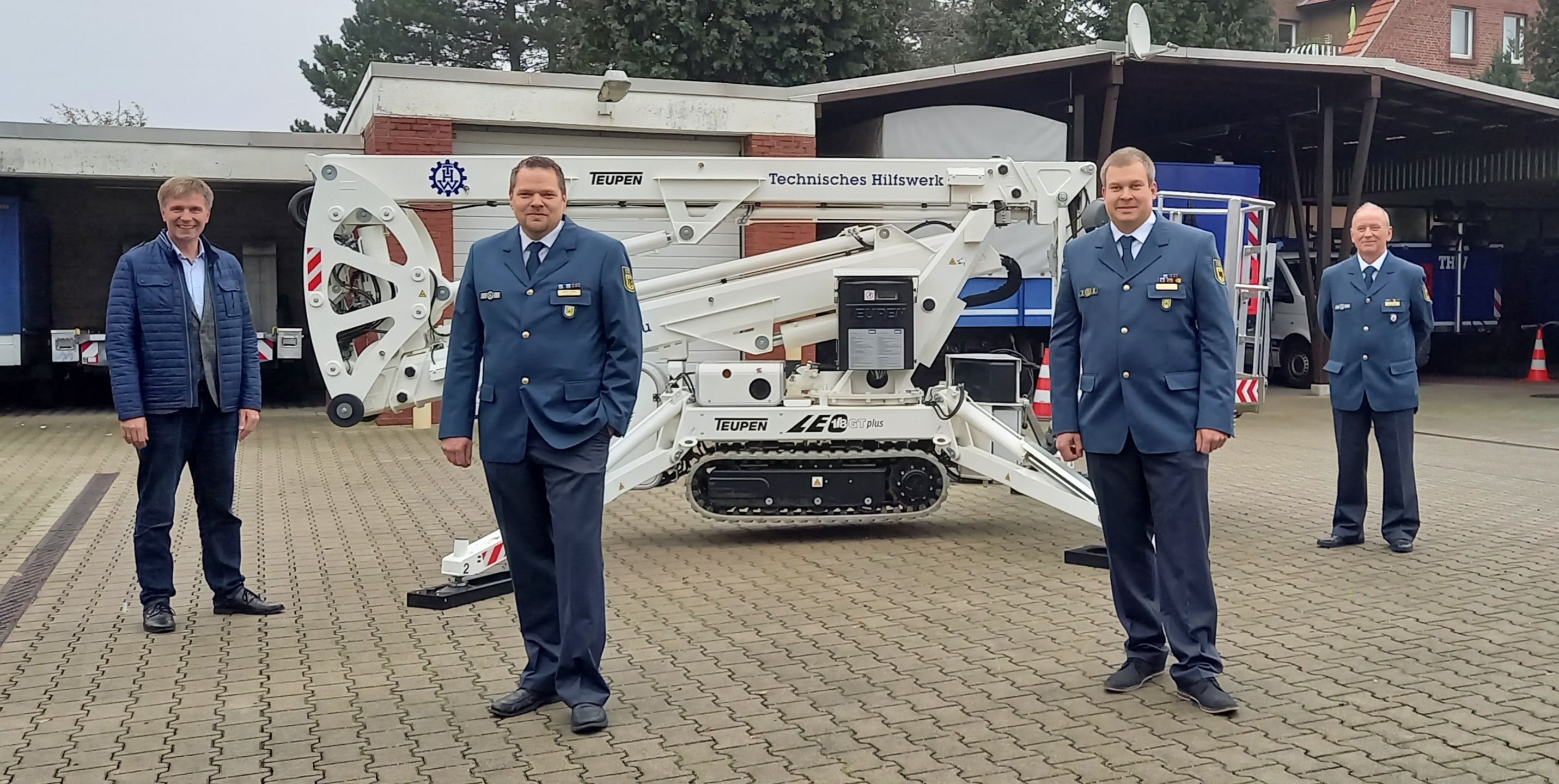 Sie sehen vier Männer vor einer Gelenkhebebühne des THW