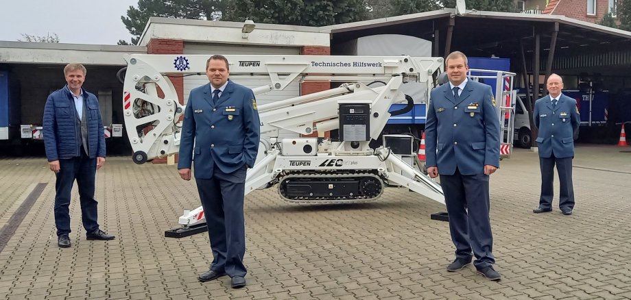 Sie sehen vier Männer vor einer Gelenkhebebühne des THW