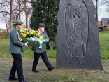 Sie sehen zwei Vertreter des Schützenvereins, wie sie den Kranz zum Ehrenmal tragen