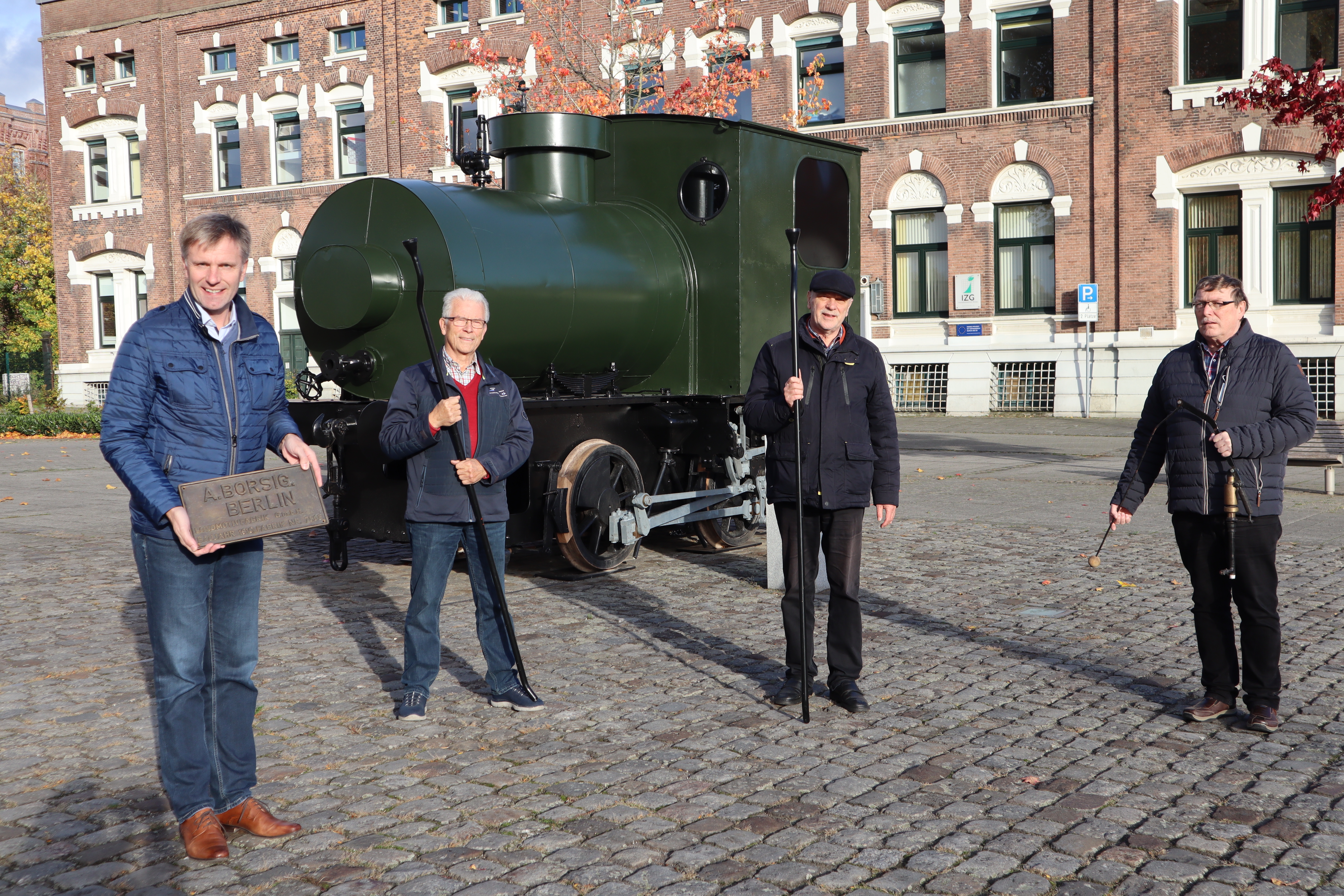 Gruppe Menschen vor der Dampfspeicherlok am Bahnhof