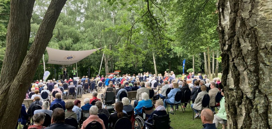 Publikum sitzt auf Stühlen vor der Waldbühne.