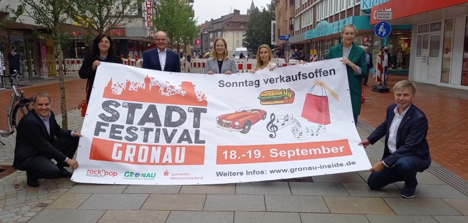 Alle Beteiligten freuen sich auf das Stadtfest und halten das Plakat zum Stadtfest hoch.