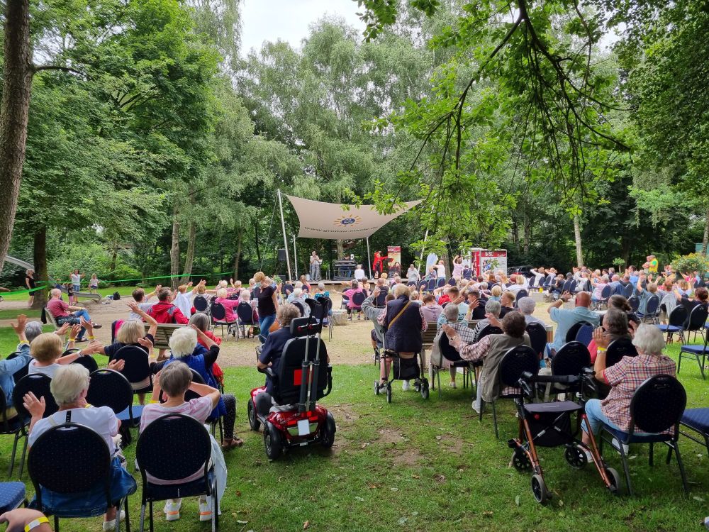 Mehrere Leute sitzen auf Stühlen vor der Waldbühne.