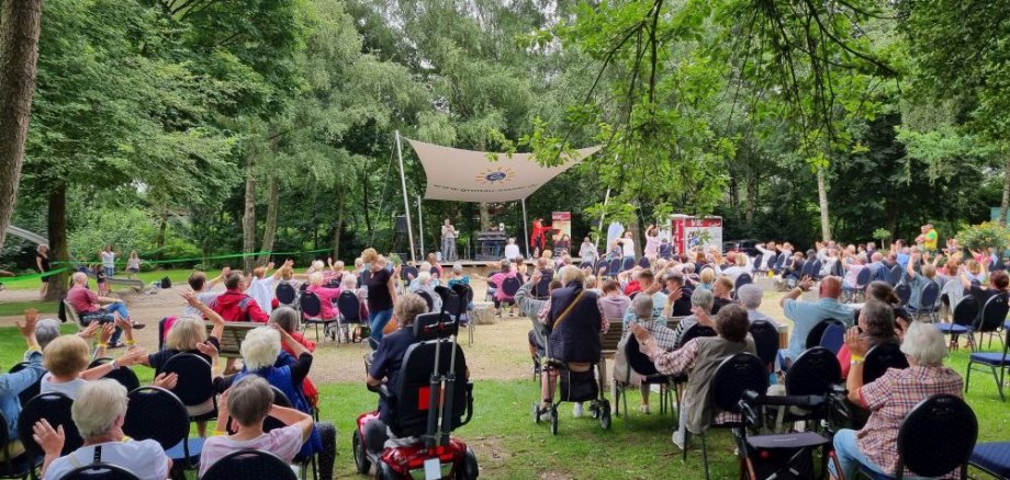 Mehrere Leute sitzen auf Stühlen vor der Waldbühne.