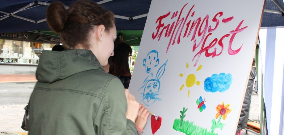 Auf einem Plakat, welches von zwei Personen bemalt wird, steht Frühlingsfest.