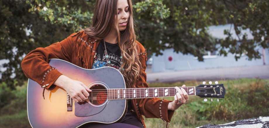 Die Musikerin DanaMaria spielt auf einer Gitarre.