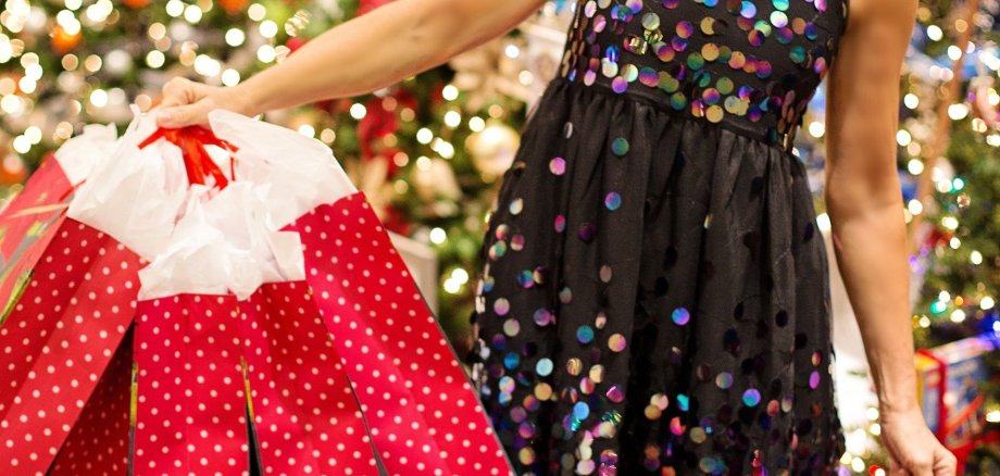 Eine Frau hält weihnachtliche Einkaufstüten in der Hand.