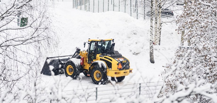 Ein Räumfahrzeug schiebt Schnee auf einen Haufen.