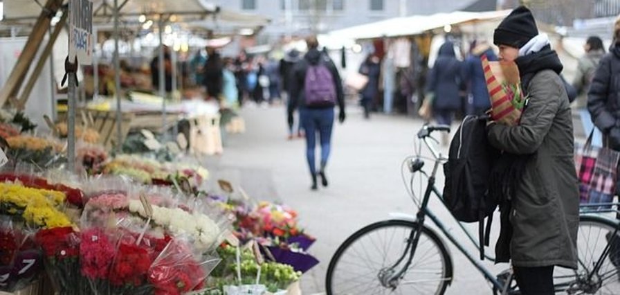 Frau mit Fahrrad auf einem Wochenmarkt