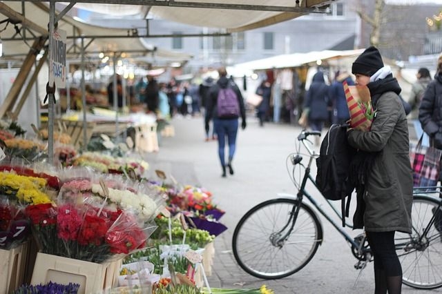 Frau mit Fahrrad auf einem Wochenmarkt
