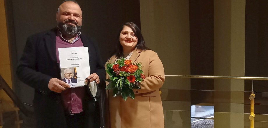 Die Eheleute Katya und Jan Acar mit der Patenschaftsurkunde und einem Blumenstrauß.
