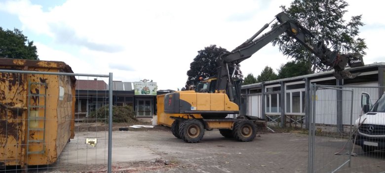 Der Bagger fängt an das Gebäude abzureißen.