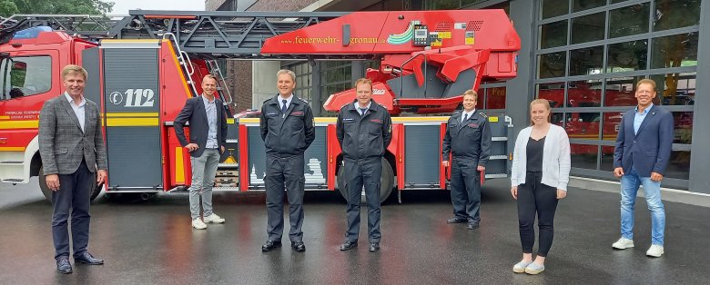 Personen vor einem Feuerwehrfahrzeug