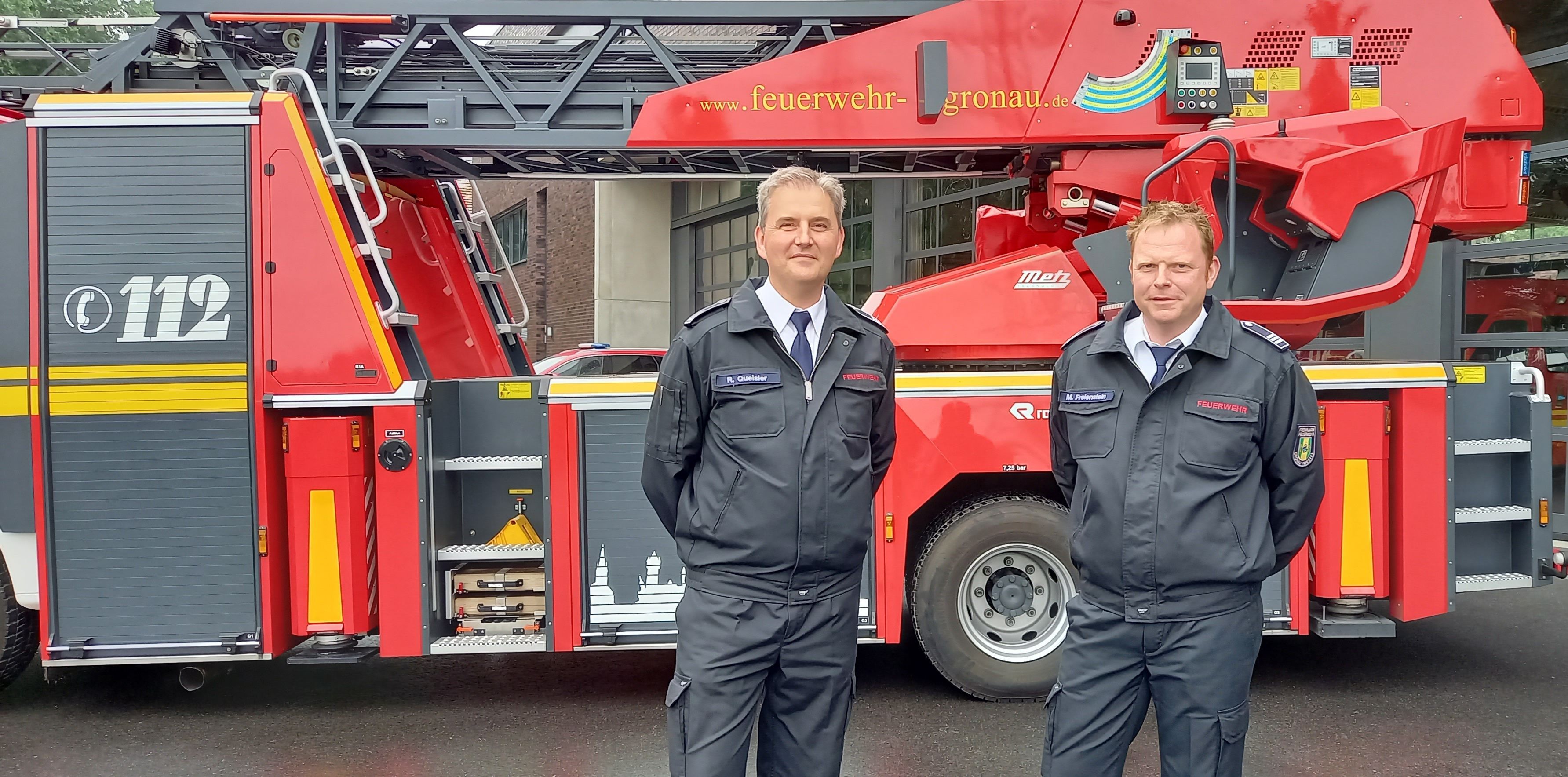 Zwei Feuerwehrleute vor einem Feuerwehrfahrzeug