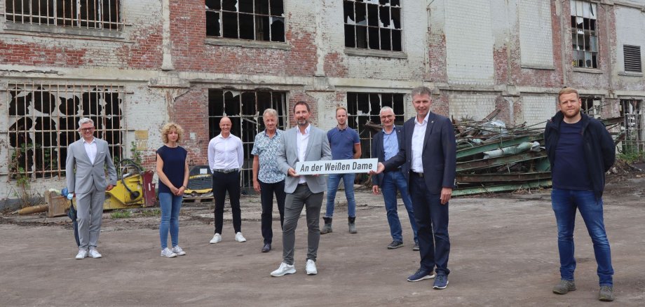 Im Beisein der Projektbeteiligten übergibt Bürgermeister Rainer Doetkotte das Straßenschild an den Geschäftsführer der Weiße Dame Gronau GmbH, Hannes Schulte.
