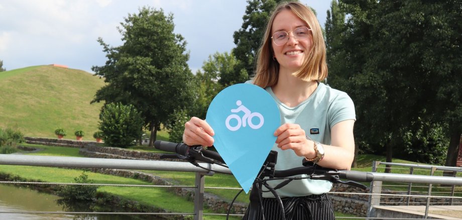 Carolin Wicke, Klimaschutzmanagerin der Stadt Gronau, hält eine Stecknadel der Klimaideenkarte in der Hand.