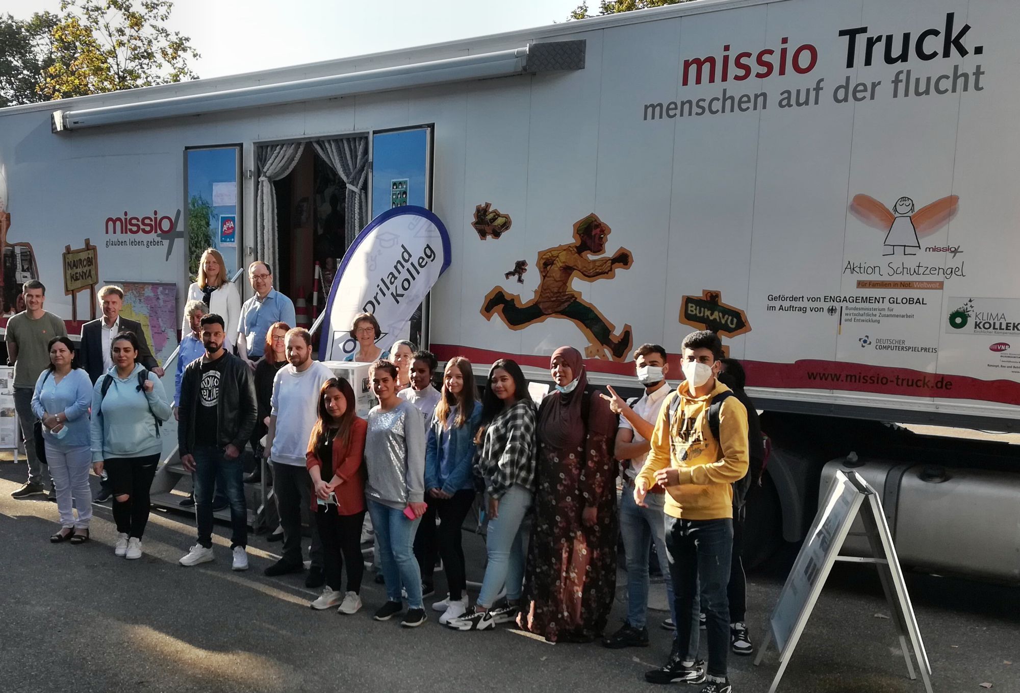 Bürgermeister Rainer Doetkotte, die Erste Beigenordnete Sandra Cichon und der Integrationsbeauftragte Ahmet Sezer gemeinsam mit interessierten Besucher*innen des Missio-Trucks.