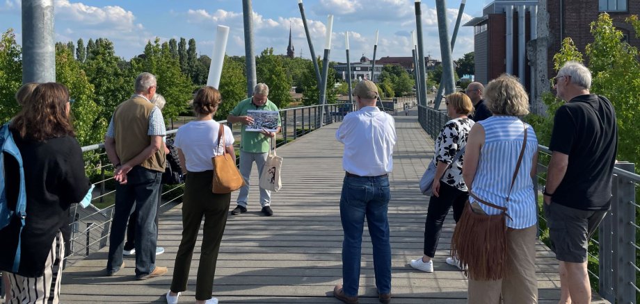 Mehrere Gäste hören Klaus Wiedau bei einer Stadtführung zu.