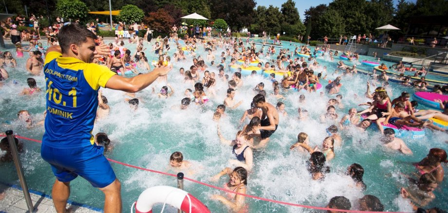 Badegäste feiern bei einer Pool-Party im Freibad.