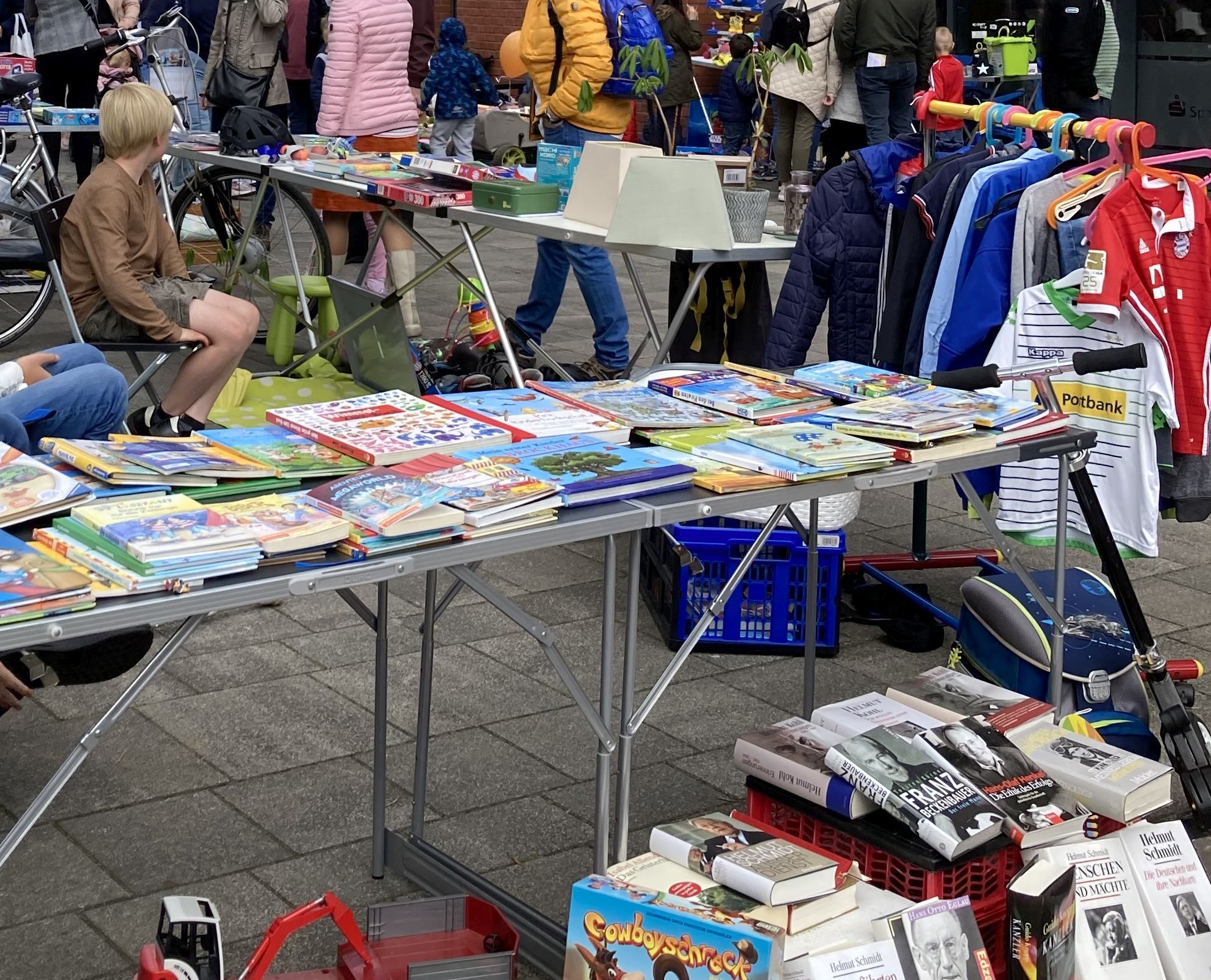 Flohmarkt mit einem Stand mit Büchern, Spielen und Kinderkleidung