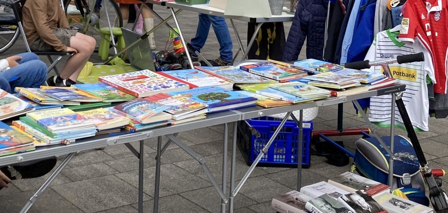 Flohmarkt mit einem Stand mit Büchern, Spielen und Kinderkleidung