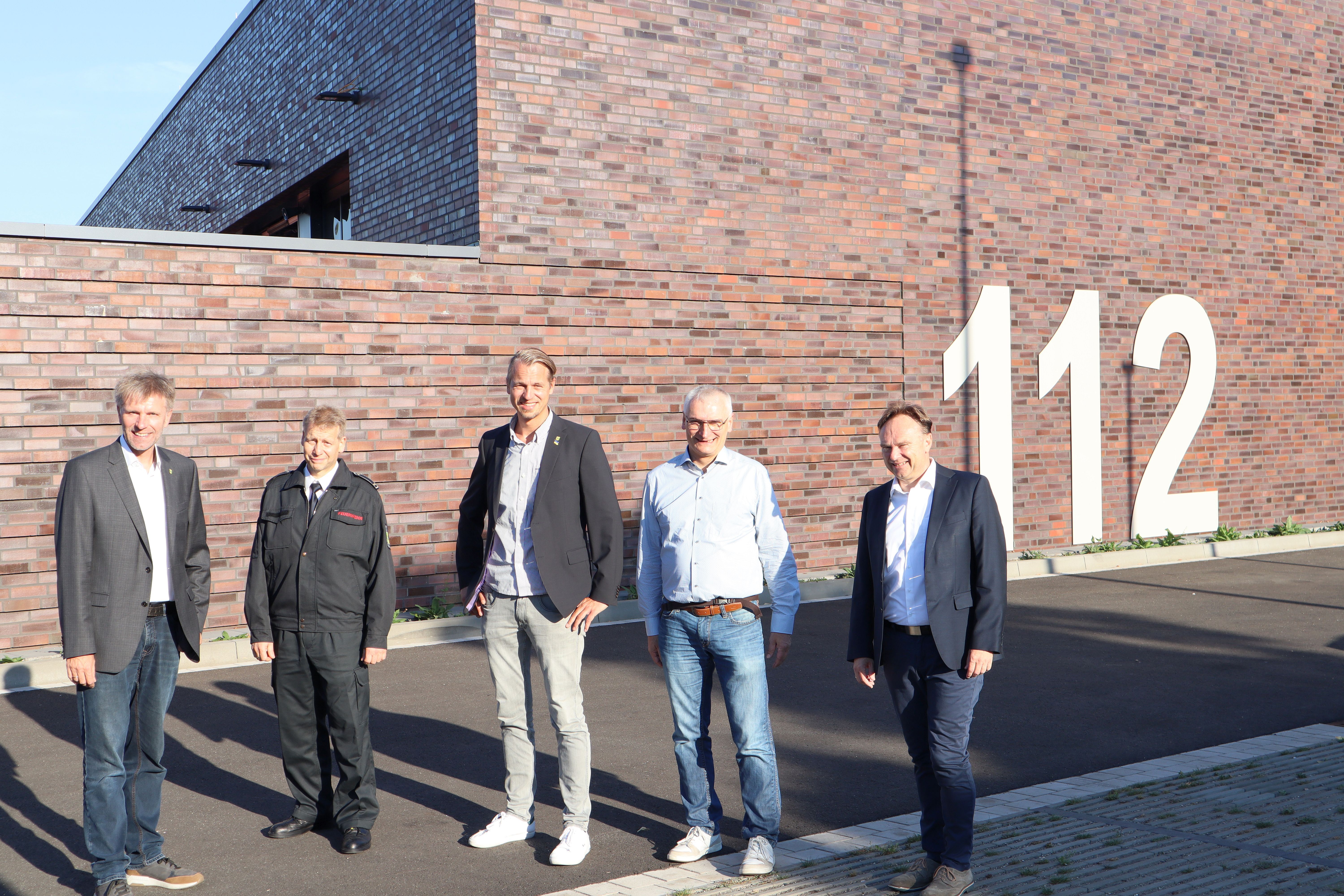 Gruppe von Menschen vor dem neuen Gebäude der Rettungswache Gronau mit Schriftzug 112