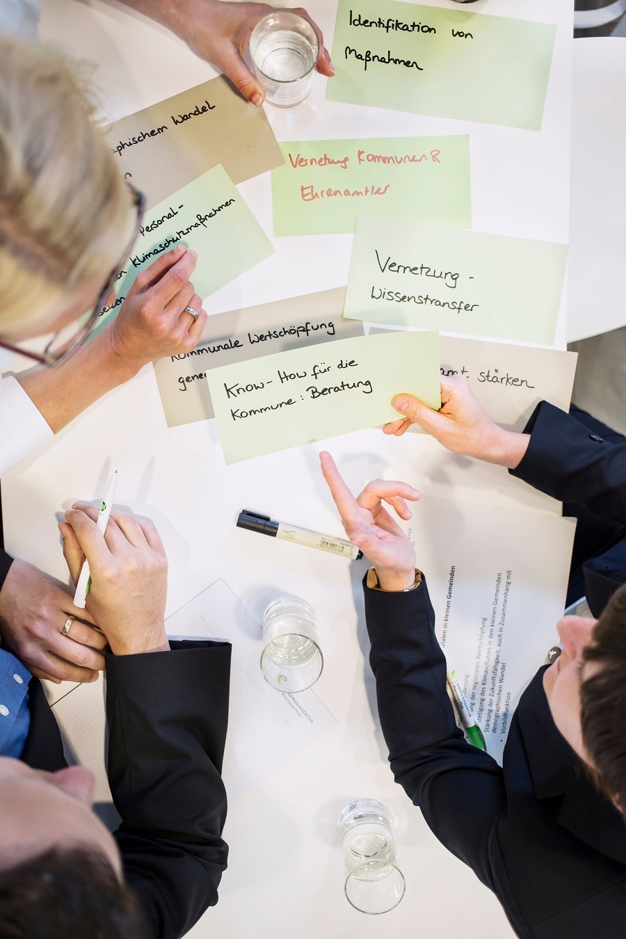 Drei Personen sammeln Stichpunkte auf Zetteln.