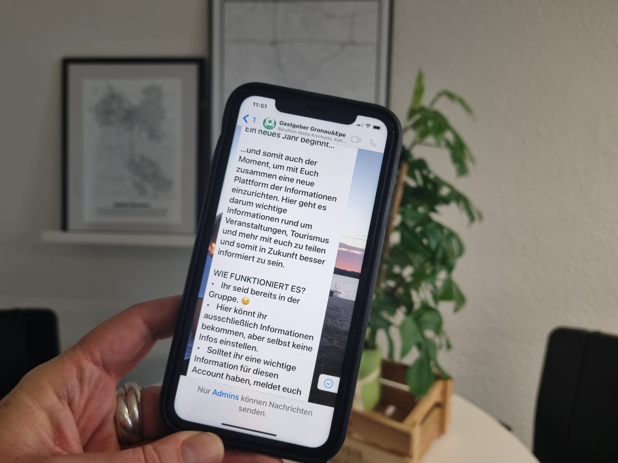 Eine Hand hält ein Handy auf dem Text zu lesen ist.