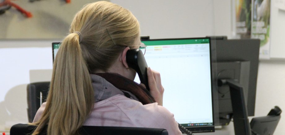 Eine Mitarbeiterin der Stadtwerke Gronau hält einen Telefonhörer in der Hand und schaut auf einen Bildschirm.