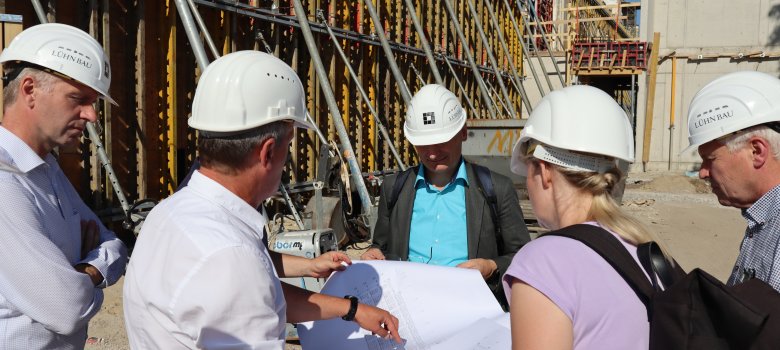 Gruppe von Menschen auf der Baustelle mit Blick auf eine Planzeichnung