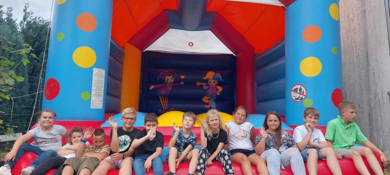 Eine Gruppe Kinder freut sich auf die Hüpfburg.