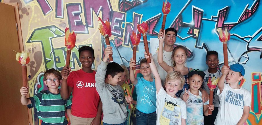 Kinder präsentieren stolz ihre gebastelten Fackeln im Jugendzentrum Stop.