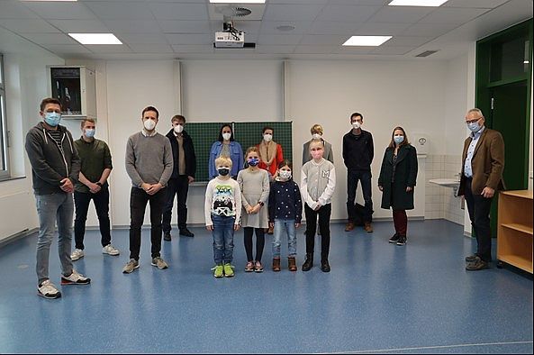 Eine Gruppe von Erwachsenen und Kindern in einem neuen Klassenzimmer