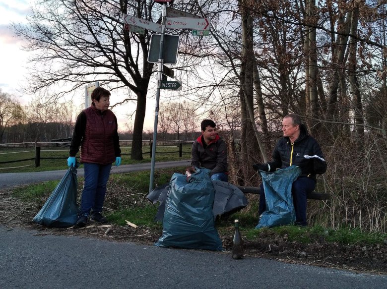 Gruppe von drei Personen mit Müllsäcken bei der Müllsammelaktion