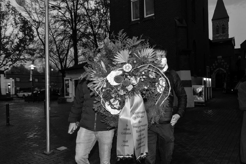 Zwei Schüler tragen einen Gedenkkranz.