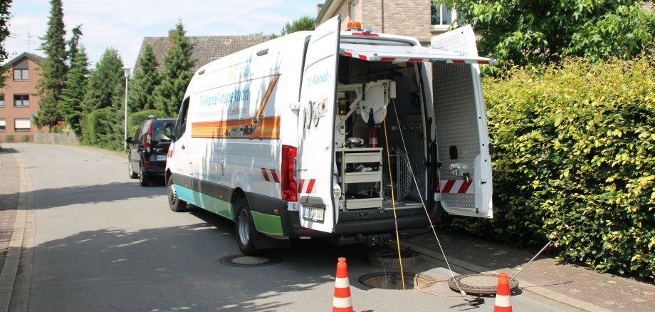 Ein Wagen der Stadtwerke vor einem offenen Gullydeckel.