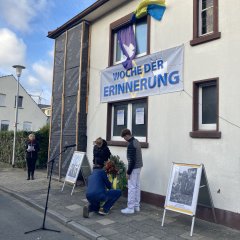 Der Bürgermeister und zwei Schüler der Euregio Gesamtschule legen Blumen nieder und stellen den Kranz auf.