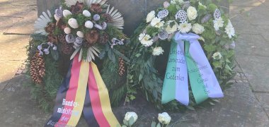 Kränze und Rosen zum Gedenken der Opfer vor dem Denkmal.