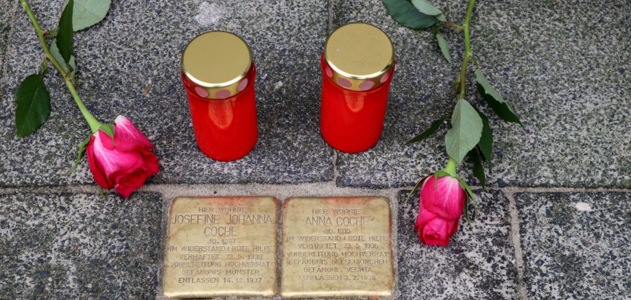 Zwei Stolpersteine mit Kerzen und Blumen