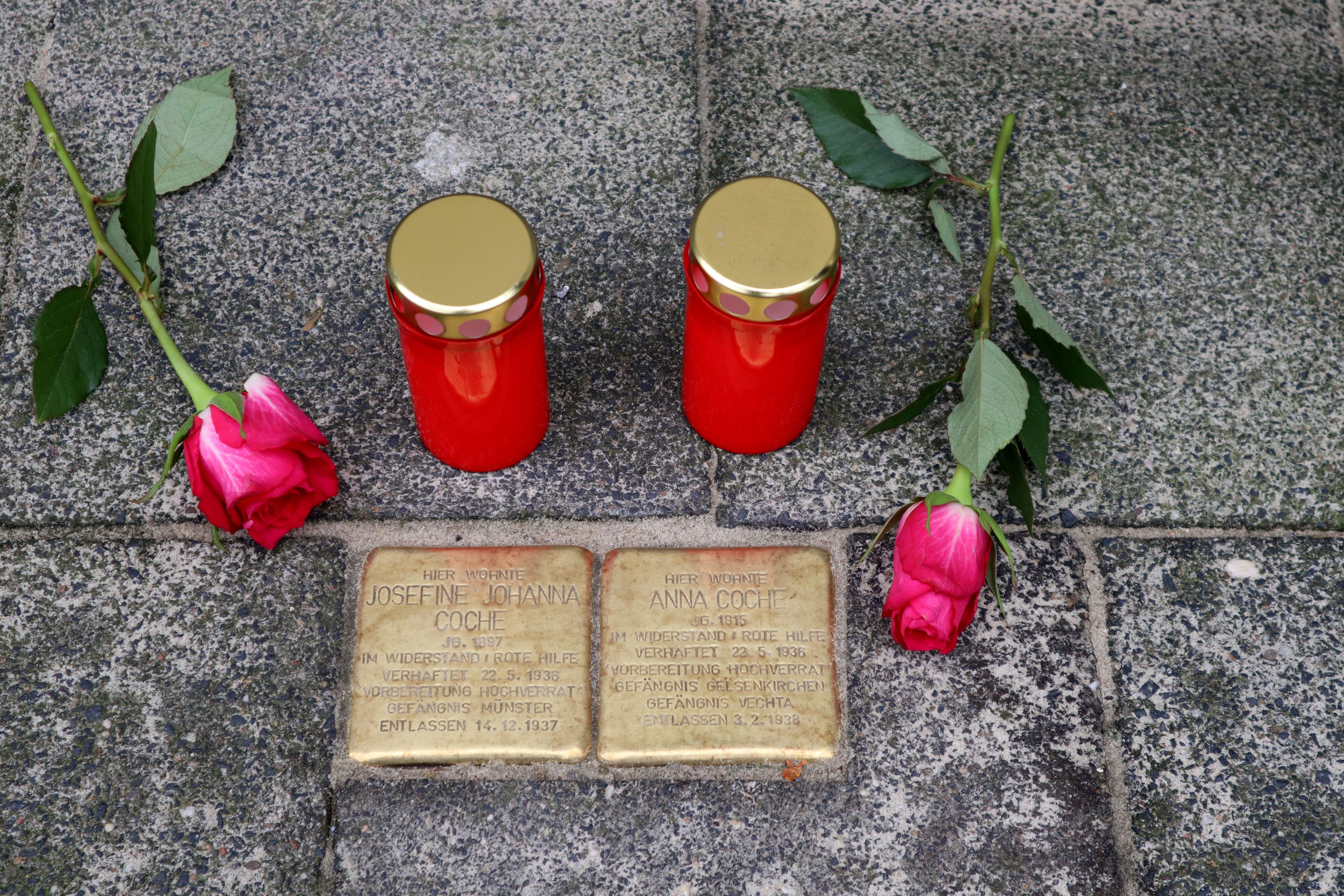 Zwei Stolpersteine mit Kerzen und Blumen