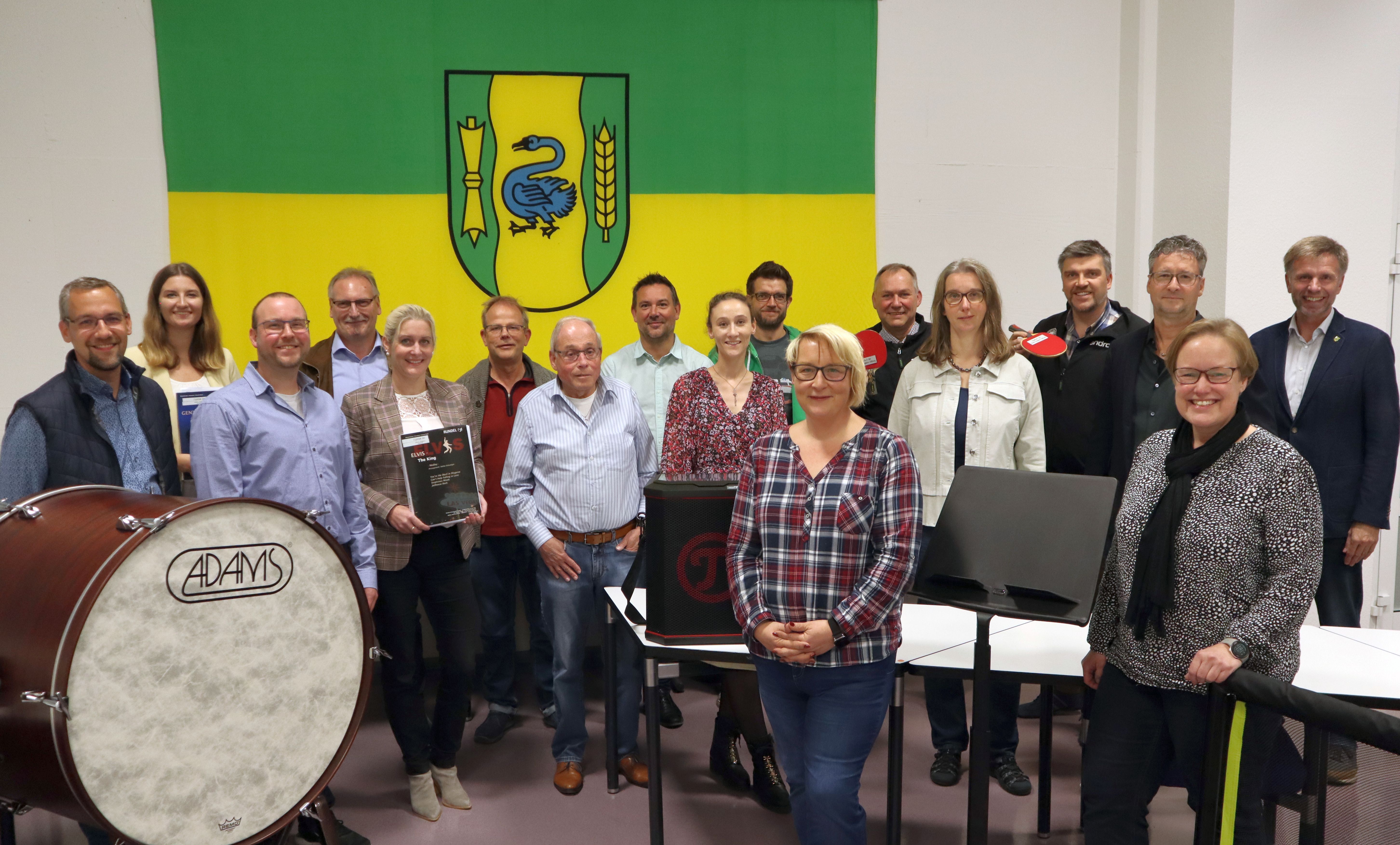 Personengruppe im Ratssaal vor der Flagge mit dem Wappen von Gronau