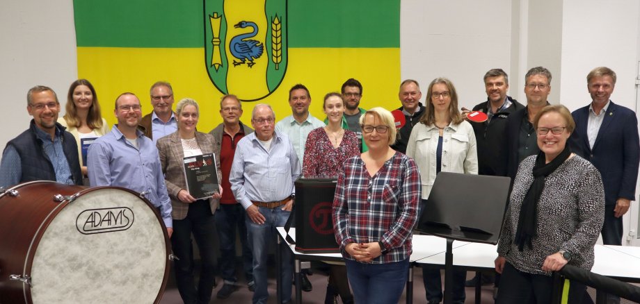 Personengruppe im Ratssaal vor der Flagge mit dem Wappen von Gronau