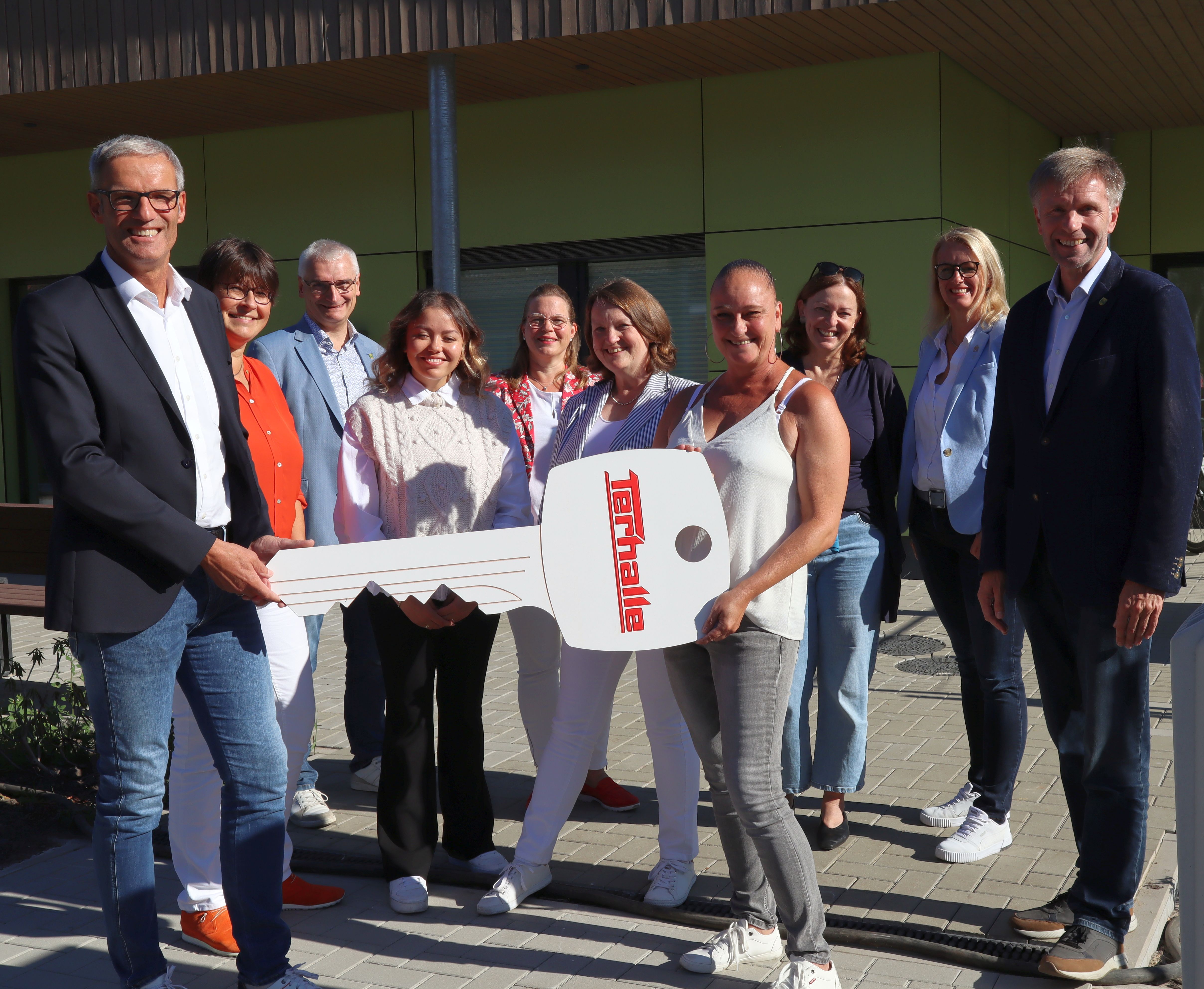 Symbolische Schlüsselübergabe mit einer Gruppe von Menschen