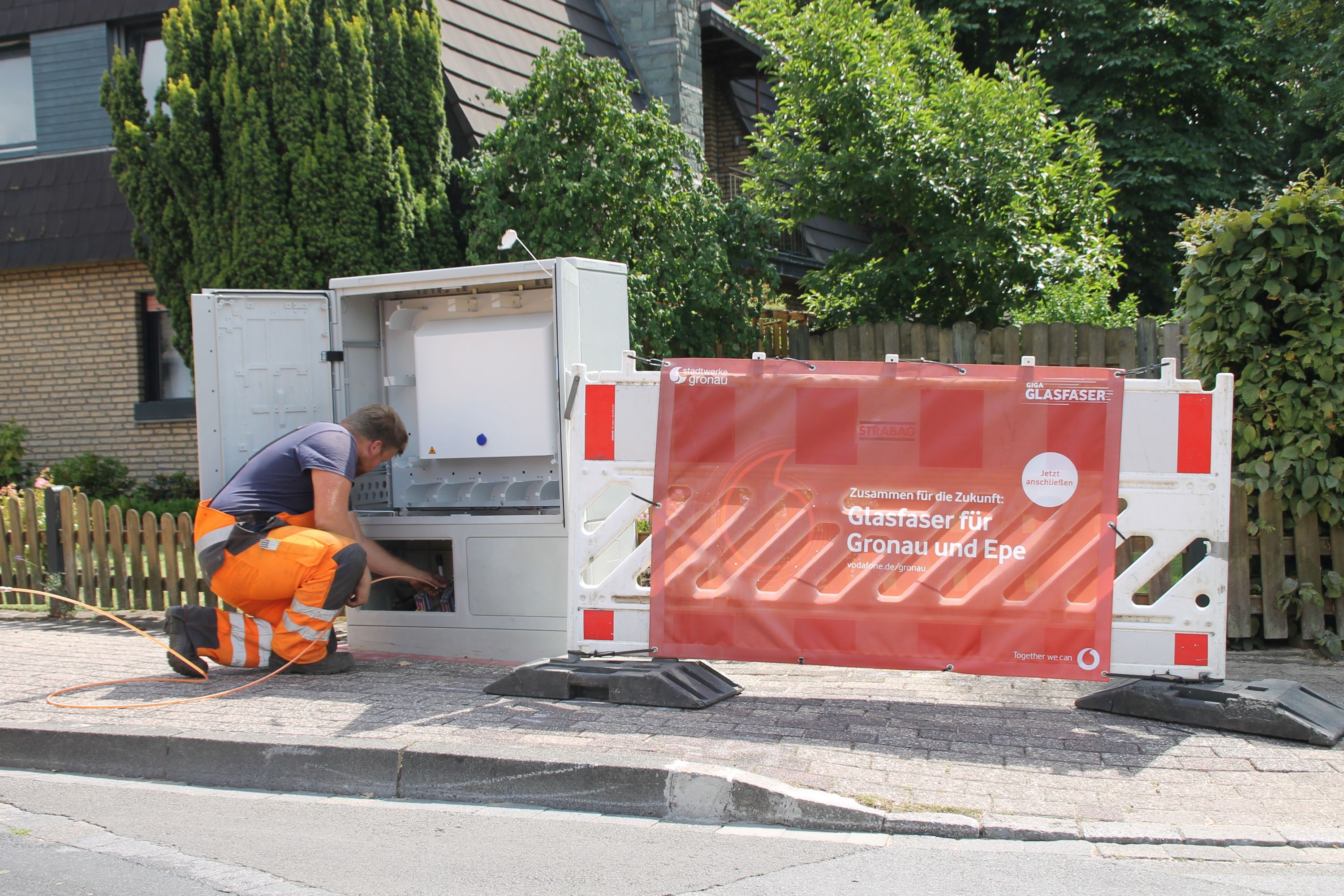 Eine Person arbeitet an einem Glasfaser-Auftrag in einer Straße.